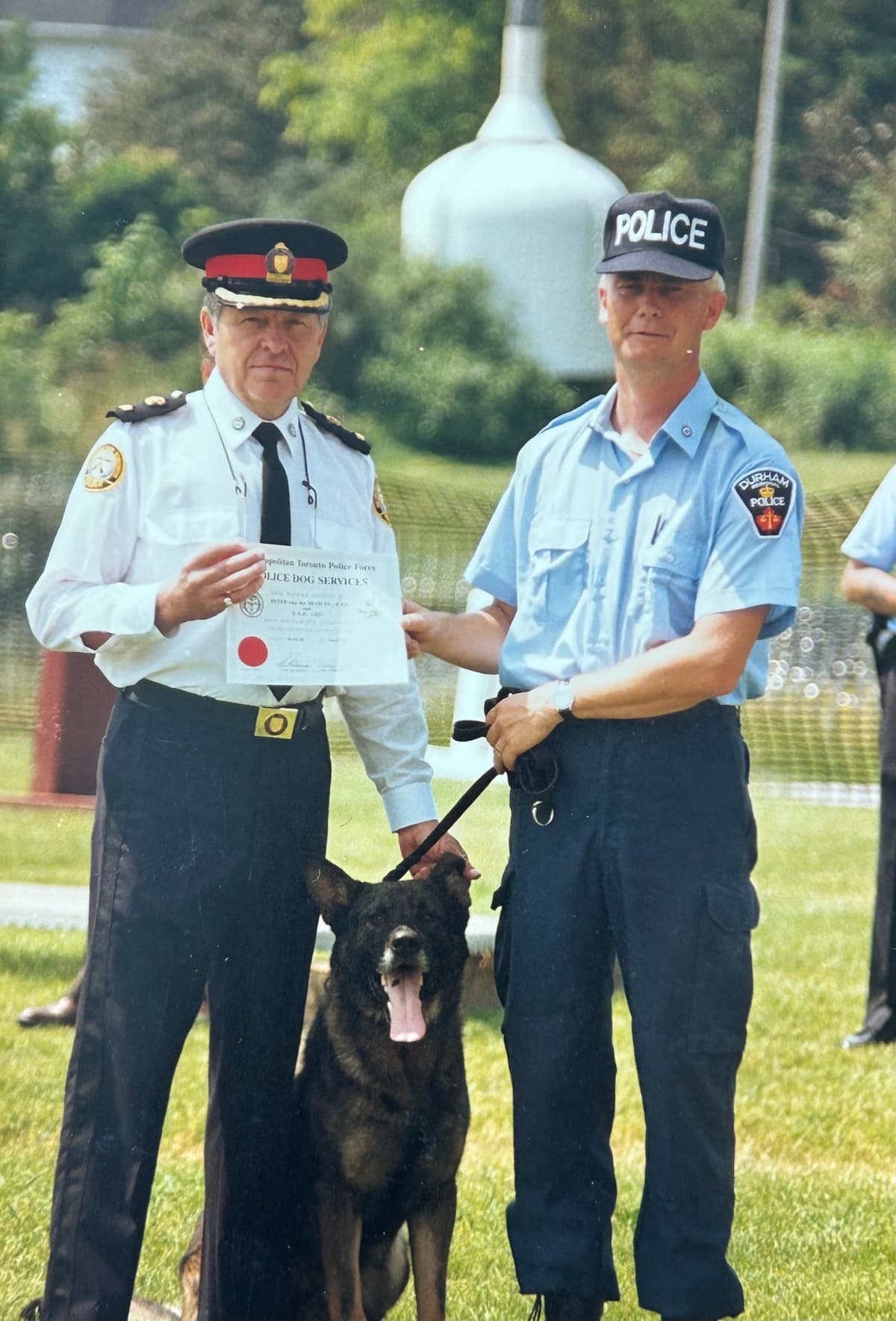 Two police officers standing next to a dog