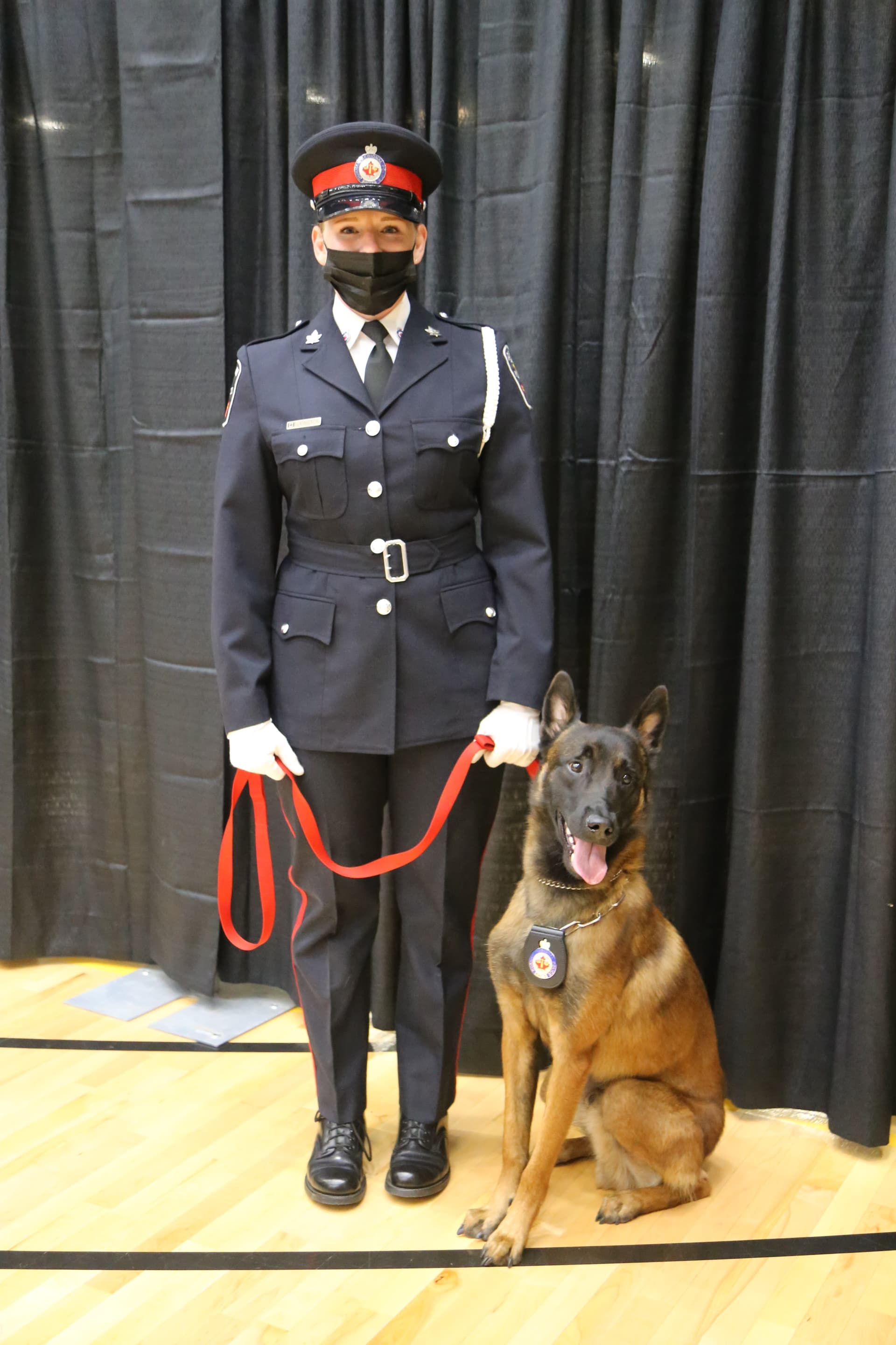 A man in uniform standing next to a dog on a leash