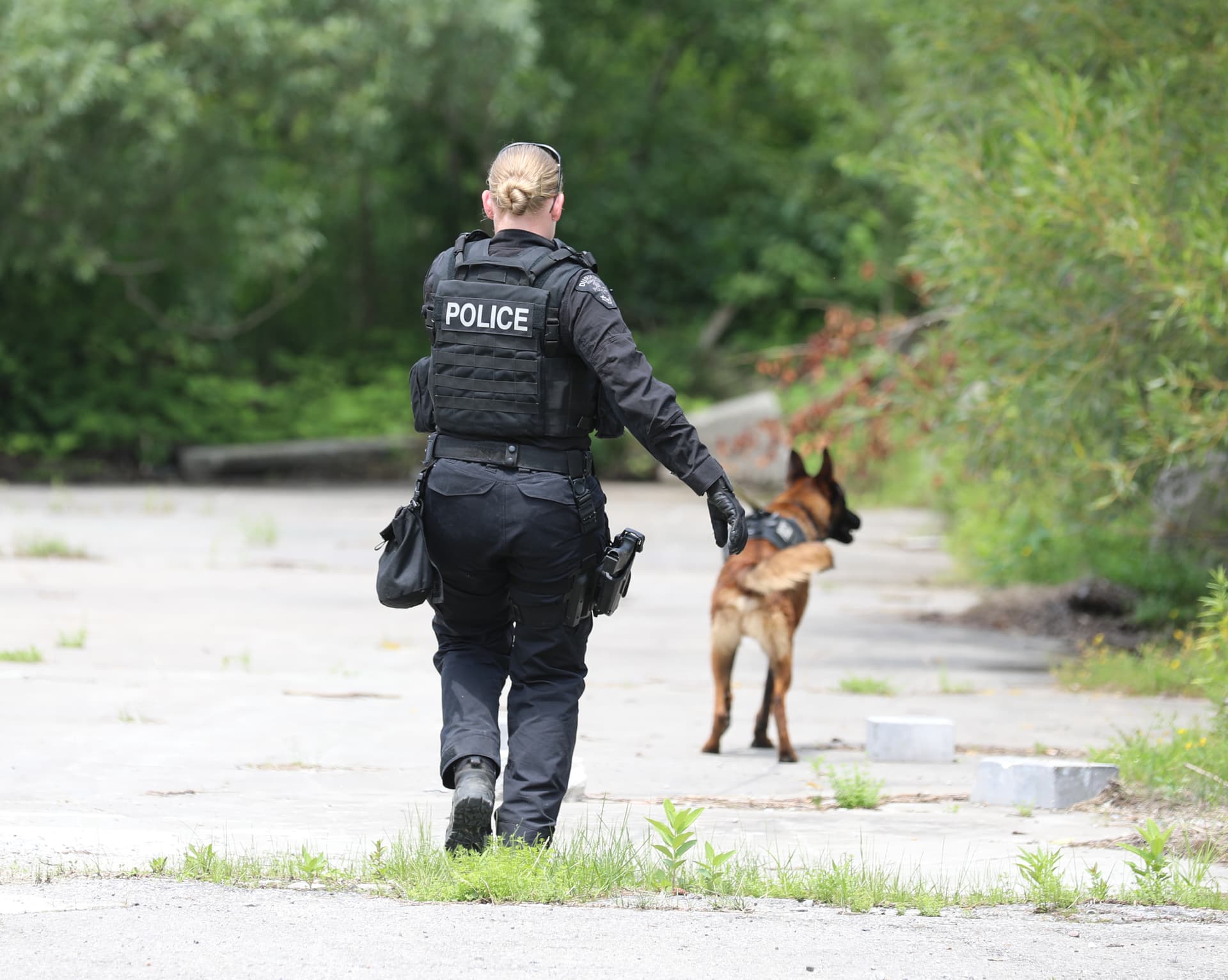 A police officer walking with a dog on a dirt road